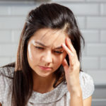 Young woman with a headache holding head. Headache, Women, Emotional Stress.
